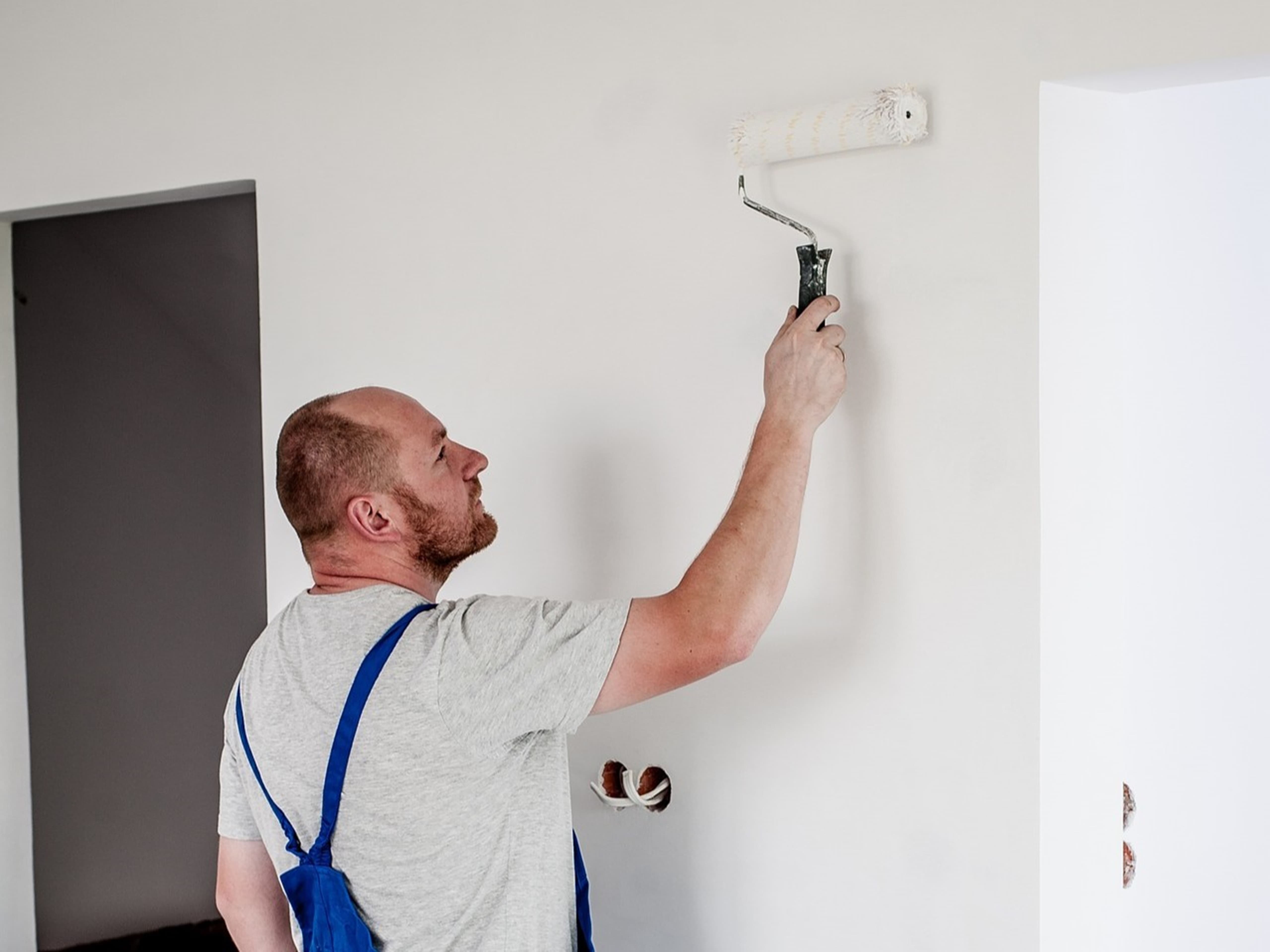Ein Verputzer / Maler von Schmück streicht eine Wand.