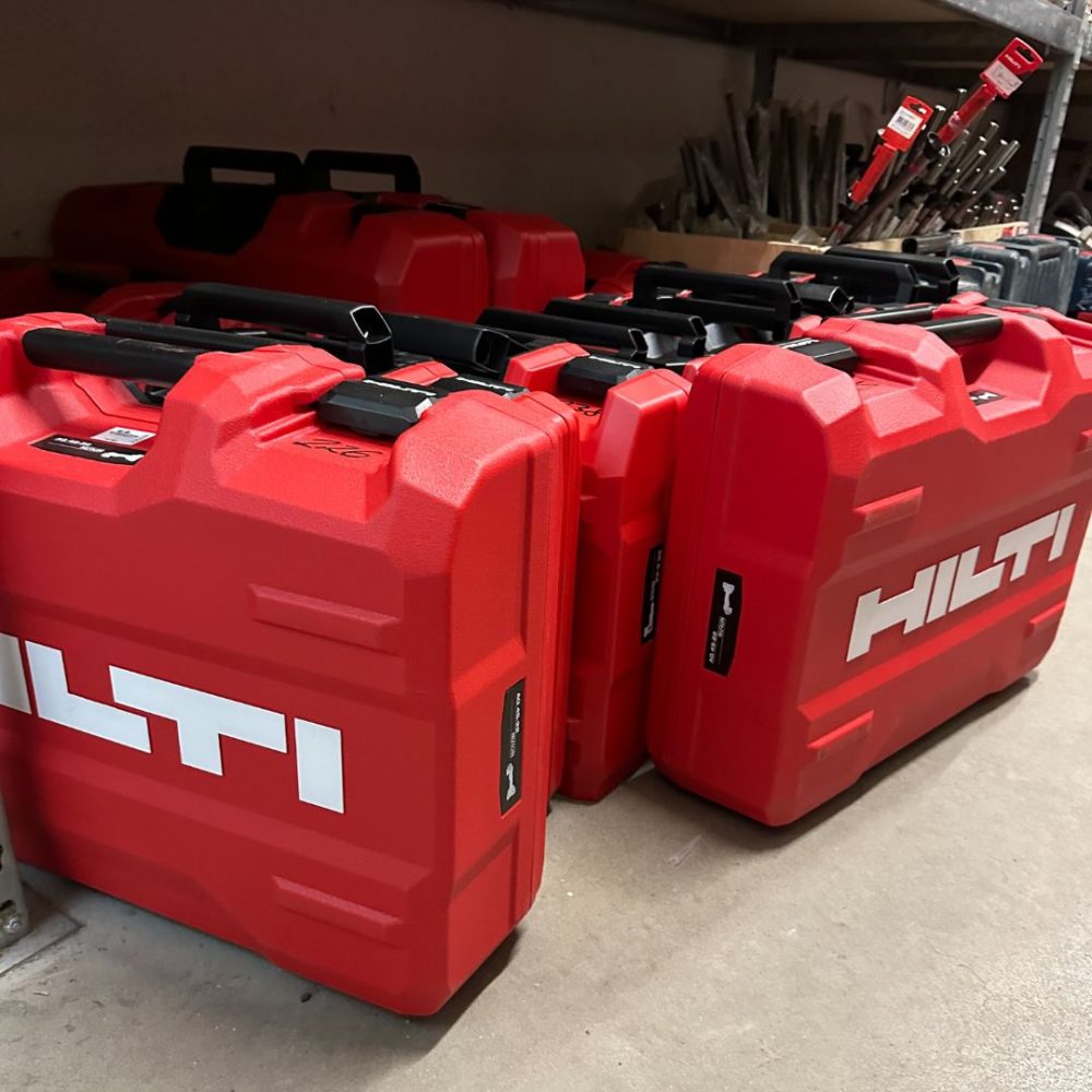 Mehrere rote Hilti-Werkzeugkoffer stehen in einem Lagerregal und sind bereit für kommende Einsätze auf unseren Baustellen.
